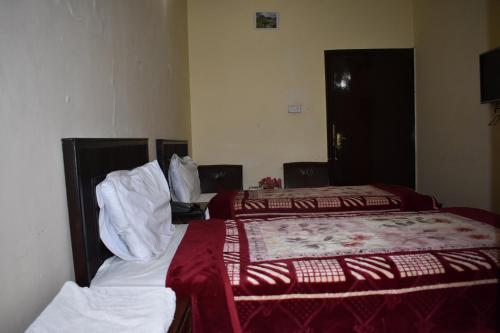 a hotel room with two beds with red and white sheets at Hotel Islamabad Residency in Islamabad