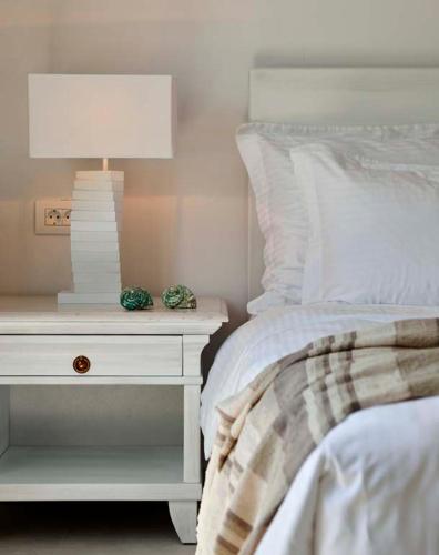 a white bed with a nightstand with a lamp on it at Petinos Beach Hotel in Platis Yialos Mykonos
