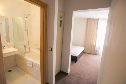 La salle de bains est pourvue d'une baignoire, d'un lavabo et d'une douche. dans l'établissement Hotel International, à Băile Felix