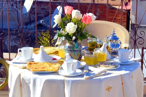 a table with a white table cloth and a vase of flowers at Riad Meyssane Fès in Fès
