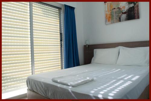a bedroom with a white bed with a window at St. George Rent Rooms in Larnaka