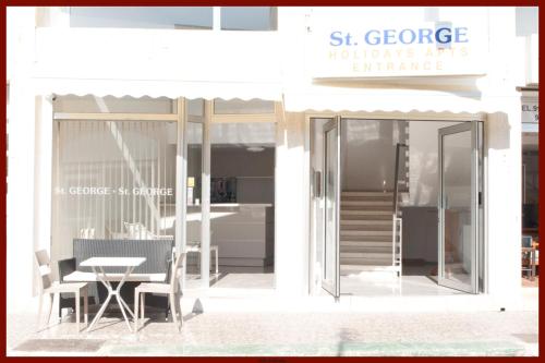 a white building with a table and a glass door at St. George Rent Rooms in Larnaca