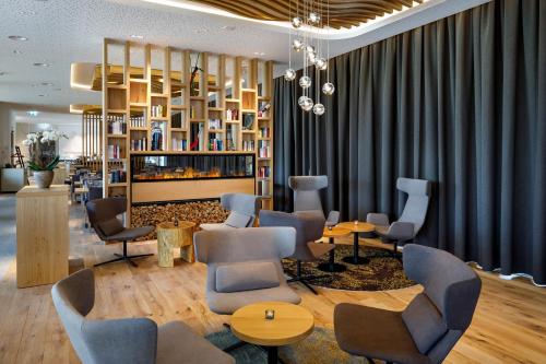 a waiting room with chairs and tables and a tv at Hotel Allegra Lodge in Kloten
