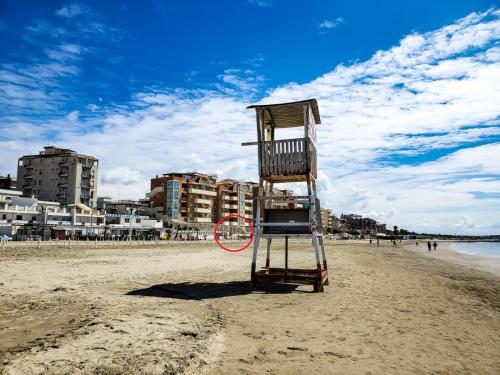 a lifeguard chair sitting on a sandy beach at Incantevole casa sul mare vicino a Roma in Nettuno