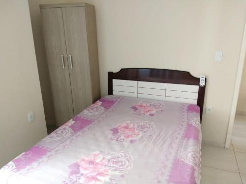 um quarto com uma cama com flores cor-de-rosa em Residencial Melfi 3 Ap. 7 Fundos em Bombinhas