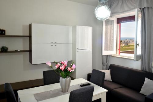 un soggiorno con divano e tavolo con fiori di Goccia Bianca - Gocce sul Mare a Savelletri