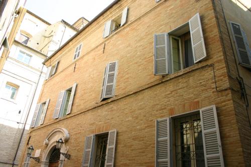 un edificio de ladrillo con ventanas y persianas. en Resort a Palazzo B&B, en Fermo