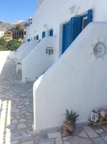 a white building with blue doors and a plant at Ariadne Studios in Kalymnos