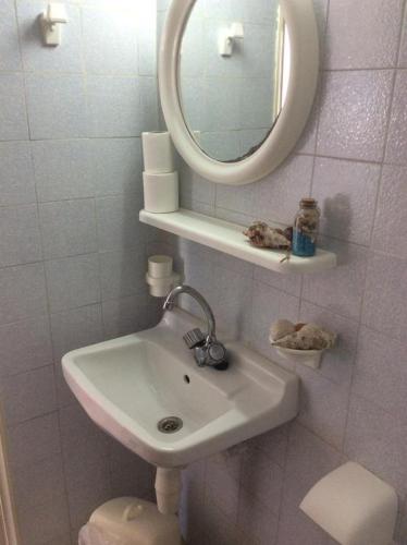 a white bathroom with a sink and a mirror at Ariadne Studios in Kalymnos