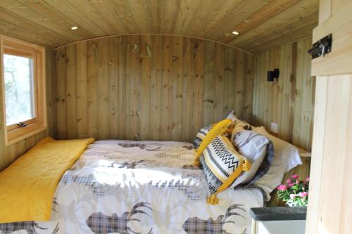 a bed in a room with a wooden wall at Shepherd's Hut - The Quirky Quarry in Middleton in Teesdale