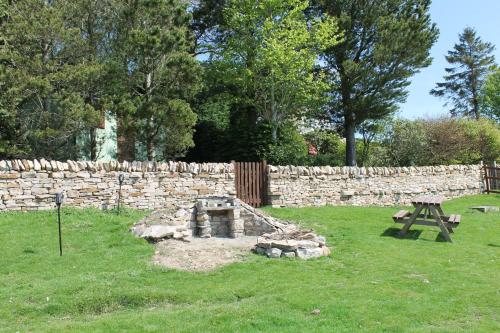 a park with a stone wall and a picnic table at Shepherd's Hut - The Quirky Quarry in Middleton in Teesdale