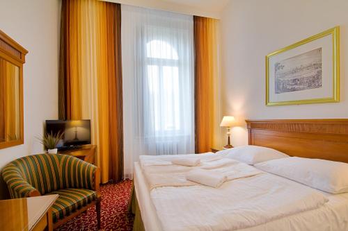 a hotel room with a large bed and a chair at Romania in Karlovy Vary