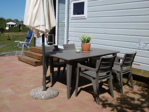 een tafel met stoelen en een parasol op een patio bij Chalet Joleen IJmuiden aan zee, vlakbij het strand in IJmuiden