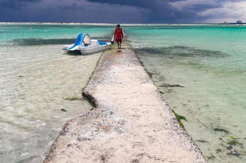 a man walking down a pier with a boat in the water at Parco del Caribe in Boca Chica