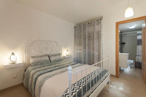 1 Schlafzimmer mit einem weißen Bett und einem Badezimmer in der Unterkunft Lets Holidays Mediterranean apartment 3 minutes to the beach 3 in Tossa de Mar