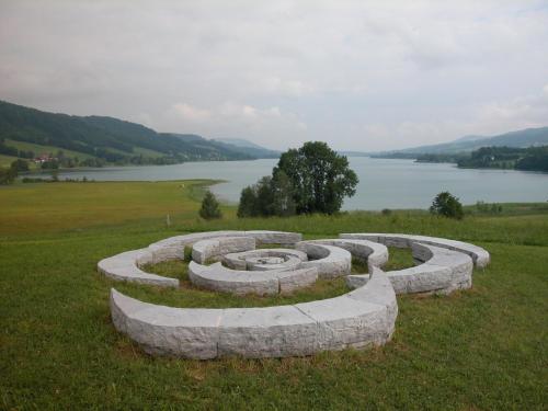 a stone circle in the grass next to a lake at Seehotel Garni Pöllmann in Mondsee