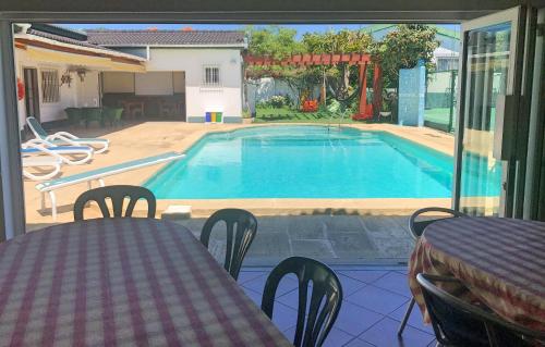 uitzicht op een zwembad met een tafel en stoelen bij Manawa Camp in Costa da Caparica