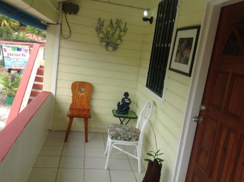 a small porch with two chairs and a table at Rainbow Beach Apartments & Rooms in Calibishie
