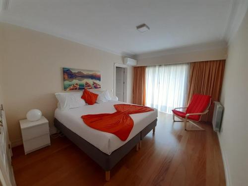 a bedroom with a large bed and a red chair at Vila Porto in Vila Nova de Gaia