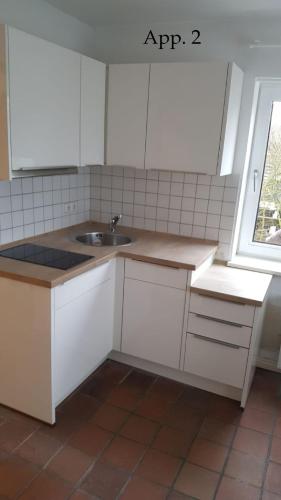 a kitchen with white cabinets and a sink and a window at Lütje Gaadt 17 c in Westerland