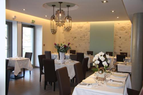 un restaurant avec des tables blanches, des chaises noires et des fleurs dans l'établissement hotel du Rhône, à Seyssel