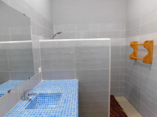 ein Bad mit blauen Fliesen und einer Dusche mit einer Bank in der Unterkunft CAP BAY in Cap Skirring