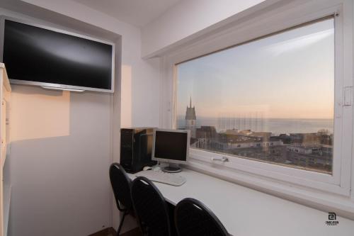 a room with a desk with a computer and a window at Skyhostel Friedrichshafen in Friedrichshafen