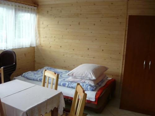 um pequeno quarto com uma cama, uma mesa e cadeiras em Domki Sara em Władysławowo