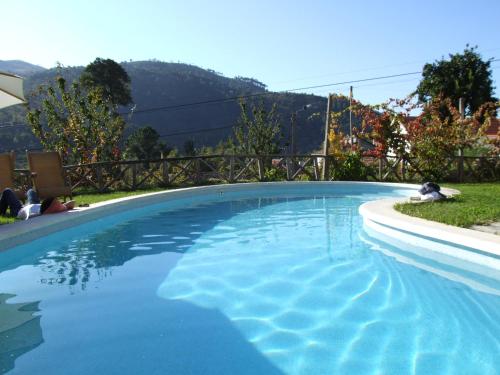 uma grande piscina com água azul num quintal em Casa do Moleiro em Cinfães