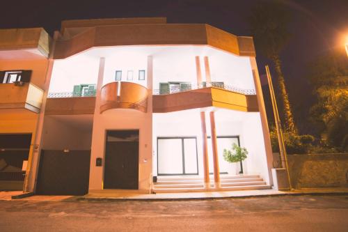 a large white house with a balcony at night at Luxury B&B Coccolhouse in San Cesario di Lecce
