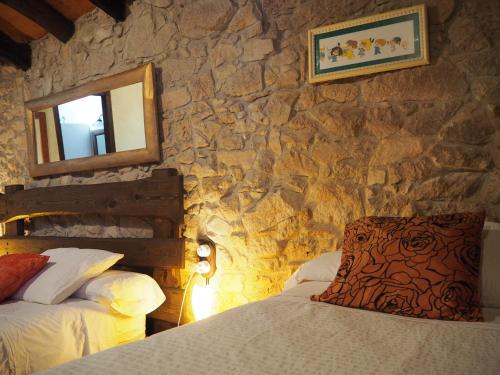 a bedroom with two beds and a stone wall at Mas Cal Sastre in Sant Hilari Sacalm