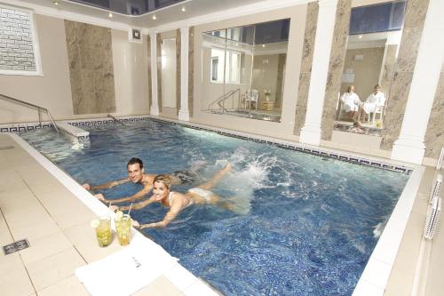 un uomo e una donna che nuotano in una piscina di Hotel Lafonte a Karlovy Vary