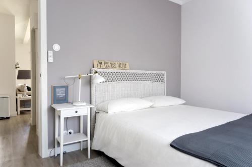 a white bedroom with a bed and a night stand at Apartamento modeno e acolhedor com terraço in Montijo