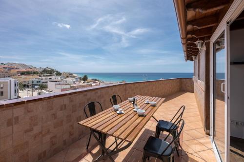 a wooden table on a balcony with a view of the ocean at attico vista oceano e città 3 camere 3 bagni WiFi AC in Morro del Jable