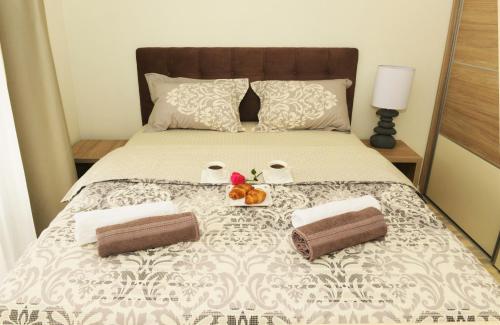 a bed with two towels and a bowl of fruit on it at Ralux apartman Tivat in Tivat