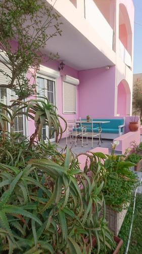 una casa rosa con un banco azul y algunas plantas en Livadi Apartments, en Plakias