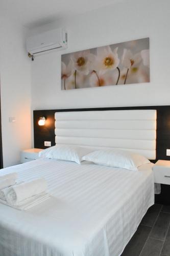 a white bed with white pillows and a painting on the wall at Flo Apartments in Ulcinj
