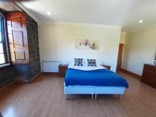 a bedroom with a bed with a blue bedspread at Quinta do Salgueiral in Peso da Régua