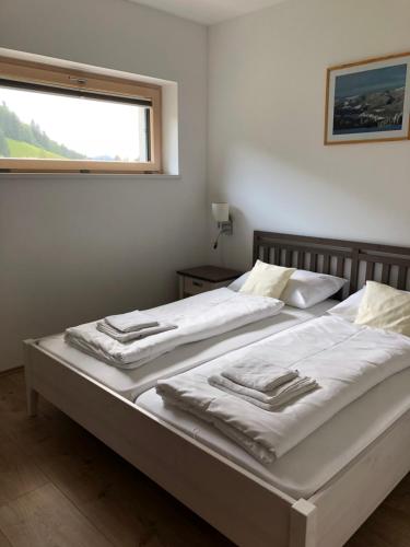 1 dormitorio con 2 camas con sábanas blancas y ventana en Haus Royal en Lackenhof