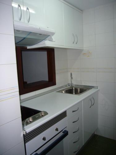 a white kitchen with a sink and a mirror at Apartamentos Gemelos IV - Fincas Arena in Benidorm