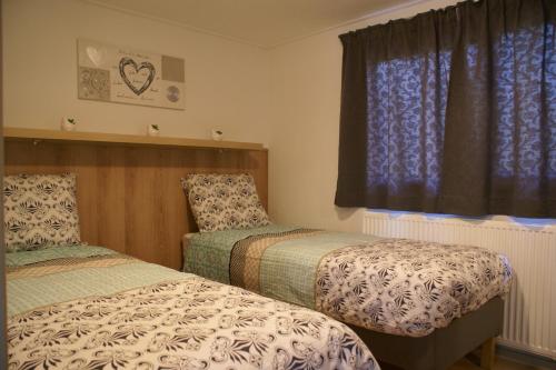 a bedroom with two beds and a window at t'Bakkersboschje nummer 8 in Putten