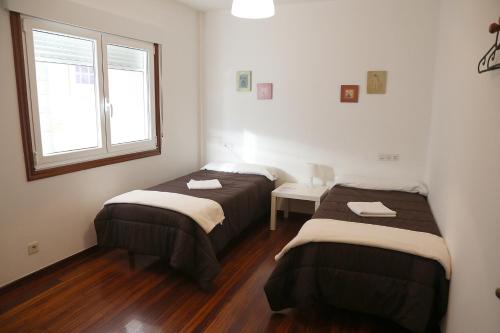 two beds in a room with a window at PENSION DE PEREGRINOS LA MODERNA in Caldas de Reis