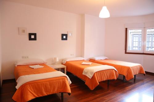 Habitación con 2 camas con sábanas de color naranja en PENSION DE PEREGRINOS LA MODERNA, en Caldas de Reis