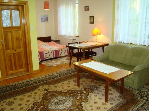 a living room with a couch and a table and a bed at Pensjonat Dworek Baranówka in Goniadz