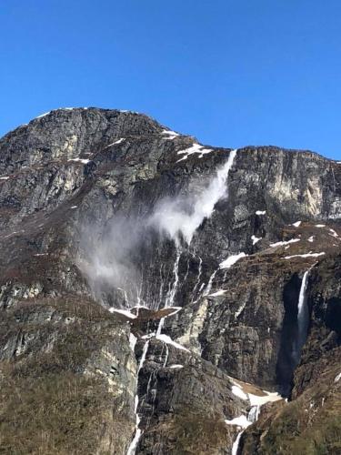 a mountain with a waterfall on the side of it at Gudvangen Camping in Gudvangen