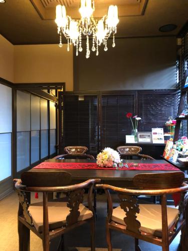 a dining room with a table and chairs and a chandelier at Guest House "Ro"kumano in Shimonoseki