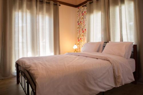 Una cama con sábanas blancas y almohadas en un dormitorio en Guesthouse Monopati - Ξενώνας Μονοπάτι, en Lechovo