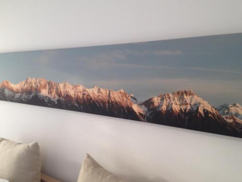 a painting of mountains on the wall of a bedroom at Sunny Apartment in Innsbruck
