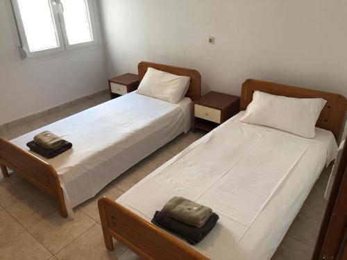 2 Betten in einem Zimmer mit 2 Tischen und 2 Kissen in der Unterkunft Irida Apartments in Nea Skioni