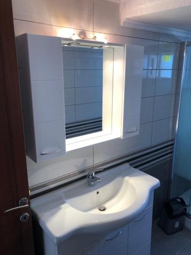 ein Badezimmer mit einem weißen Waschbecken und einem Spiegel in der Unterkunft Irida Apartments in Nea Skioni